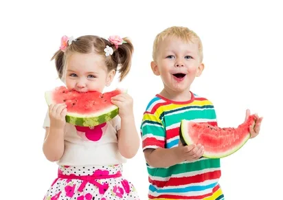 Two young children smiling as they share watermelon together.