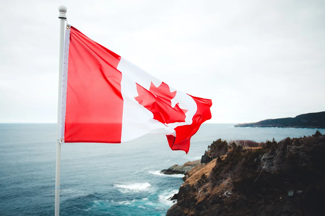 A Canadian flag flying over the coastline.