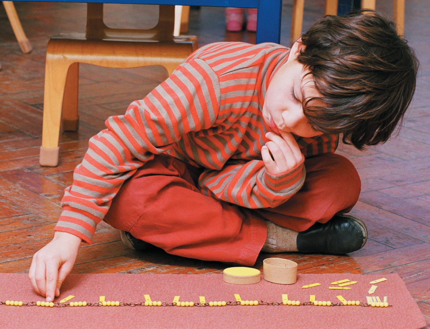 Children in a Montessori classroom in the United Kingdom focused on independent work at low tables.