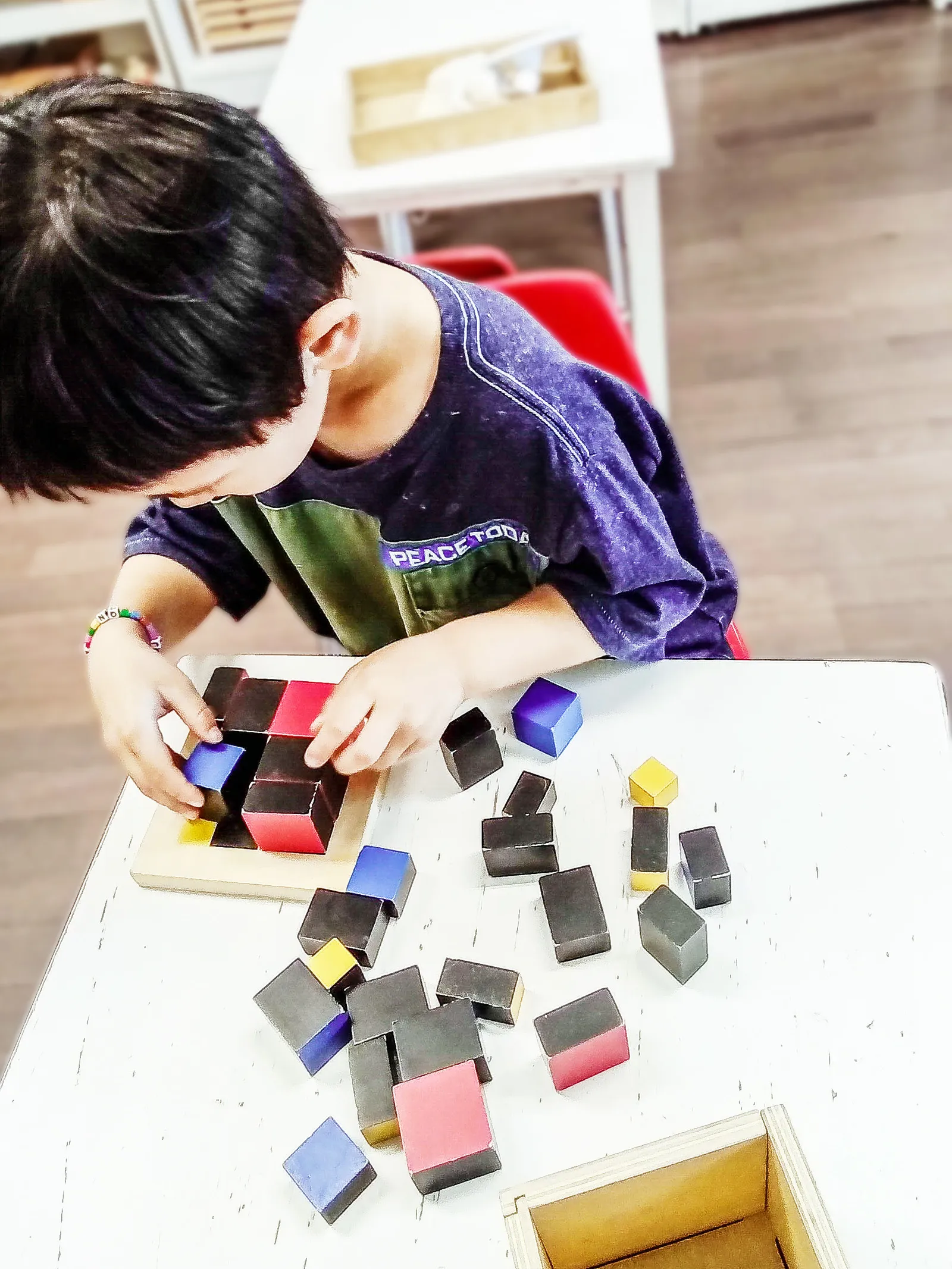 A child building with colored cube blocks in the Casa classroom.
