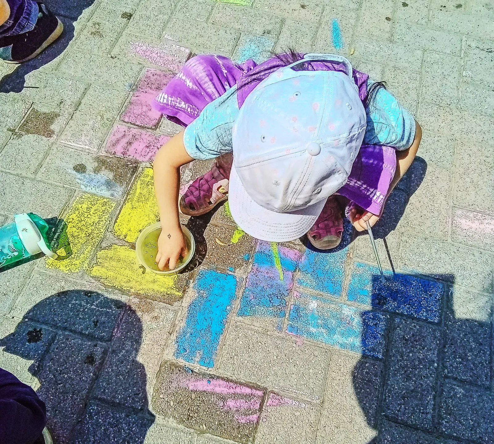 A child drawing with sidewalk chalk outdoors at ACE Montessori.