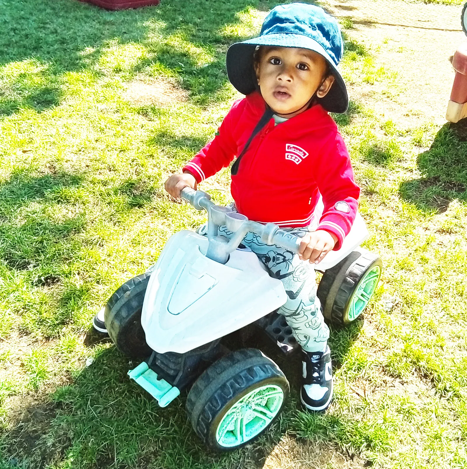 A toddler playing outdoors on a ride-on toy at ACE Montessori.
