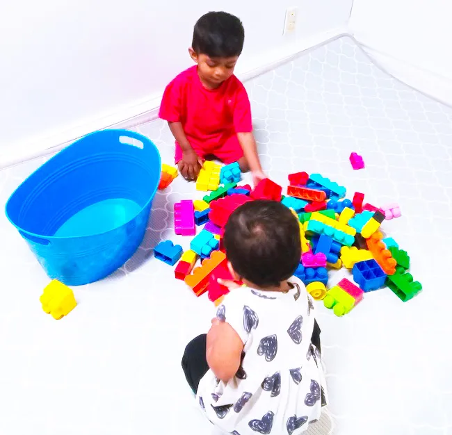 Two toddlers playing together with building blocks at ACE Montessori.